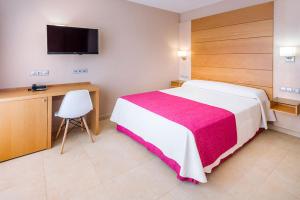 滨海罗克塔斯Mediterraneo Bay Hotel & Resort的一间卧室配有一张床、一张书桌和一台电视