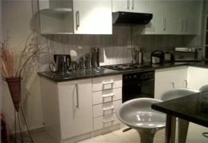 约翰内斯堡SunSet West Self Catering Maraisburg Roodepoort的厨房配有白色橱柜和炉灶烤箱。