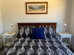 金斯科特Beachside House的一间卧室配有一张带蓝色枕头的床和两张桌子