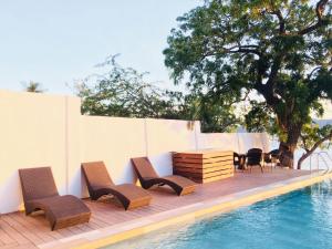 马比尼Altamare Dive and Leisure Resort Anilao的一组椅子和一张桌子,旁边是游泳池