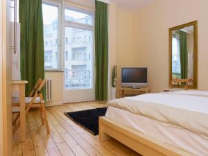柏林市中心西区比尔林城公寓的一间卧室配有一张床、一张书桌和一台电视