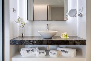 马德里易美吉因巴塞罗酒店&度假村的浴室配有盥洗盆和带毛巾的台面。