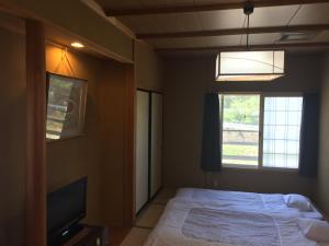 山之内町大丸屋日式旅馆的一间卧室配有一张床、一台电视和一个窗口