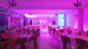 圣弗朗西斯科Hotel Nueva Ardenza的宴会厅配有白色桌子和粉红色的灯光
