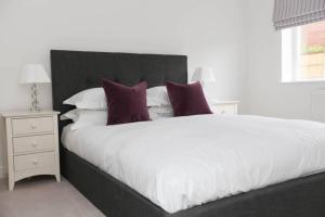 BlidworthRaynolds Cottage Blidworth的卧室配有一张带紫色枕头的大型白色床。