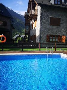 贝纳斯克Residencial Valle de Benasque的大楼前的大型蓝色游泳池