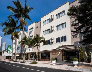 巴拉奈里奥-坎布里乌罗孙布洛克酒店的一座高大的白色建筑,前面有棕榈树