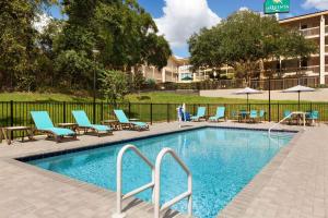盖恩斯维尔La Quinta by Wyndham Gainesville的一座带桌椅的游泳池以及一座建筑