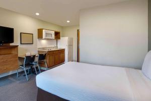 坎普泉WoodSpring Suites Washington DC Andrews AFB的一间卧室配有一张床,厨房配有冰箱
