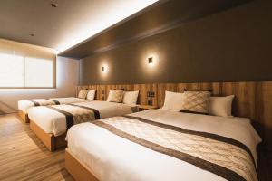 别府GRAND BASE Beppu Ekihigashi的一间酒店客房,内有三张床