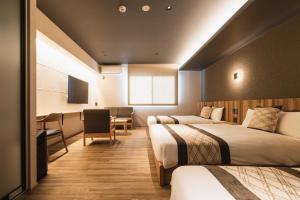 别府GRAND BASE Beppu Ekihigashi的酒店客房配有两张床和一张书桌