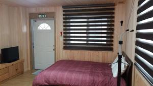 江陵市伊兹密尔度假屋的一间卧室设有床、窗户和门