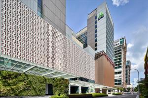 新加坡Holiday Inn Express Singapore Katong, an IHG Hotel的一座高大的建筑,旁边有一个标志