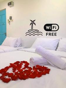 瓜拉丁加奴IBAI BEACH GUESTHOUSE的一间卧室配有两张床,床上铺有红色玫瑰