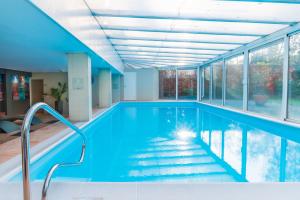 聚特芬聚特芬弗莱彻酒店的一个带蓝色海水和窗户的室内游泳池