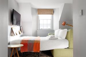 爱丁堡伊顿洛克公寓式酒店的一间卧室配有一张床、一把椅子和电视