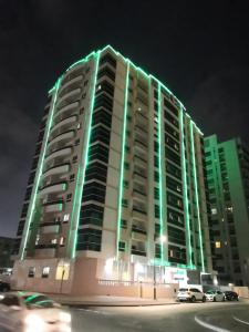迪拜林荫道城市套房酒店式公寓的一座在晚上有绿灯的大建筑