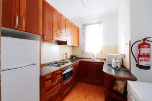 弗里希利亚纳Apartment Esmeralda Meneguina by SpainSunRentals 1121的厨房配有木制橱柜和白色冰箱。