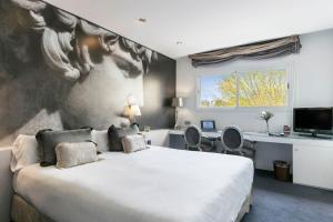 马德里全球亚西斯加勒蒂亚旅馆的卧室配有一张大床,墙上挂有绘画作品