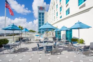 劳德代尔堡Crowne Plaza Hotel & Resorts Fort Lauderdale Airport/ Cruise, an IHG Hotel的一个带桌椅和蓝伞的庭院