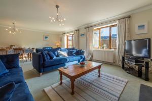 韦德布里奇Keepers Cottage的客厅配有蓝色的沙发和电视