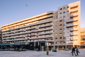 波尔图BBA Apartments Boavista - Casa da Música with Parking的一座高大的建筑,前面的人在步行