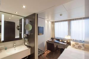 柏林雷迪森柏林亚历山大广场酒店的酒店客房带一张床、一张书桌和一面镜子