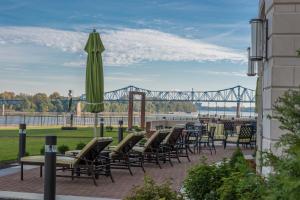 欧文斯伯勒Holiday Inn Owensboro Riverfront, an IHG Hotel的一个带椅子和遮阳伞的庭院和一座桥梁