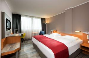 汉诺威Ramada by Wyndham Hannover的酒店客房设有一张带红色毯子的大床