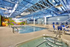 温尼伯Holiday Inn Express Winnipeg Airport - Polo Park, an IHG Hotel的一个带椅子和热水浴缸的大型室内游泳池