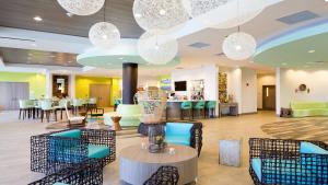 沃尔顿堡滩沃尔顿堡滩假日酒店的大堂设有桌椅和吊灯。