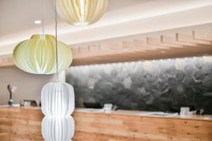 熊本REF Kumamoto by VESSEL HOTELS的两盏挂在柜台上的白色吊灯