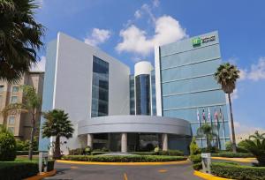 圣路易斯波托西Holiday Inn Express San Luis Potosí, an IHG Hotel的一座白色的大建筑,前面有棕榈树