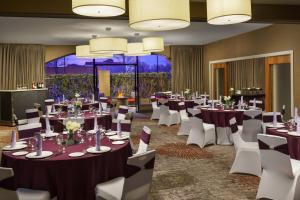 夏洛特夏洛特大学假日酒店的宴会厅配有桌子和白色椅子