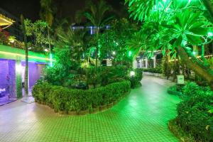 芭堤雅市中心Natural Beach Hotel Pattaya的一座带棕榈树和灯光的花园的建筑