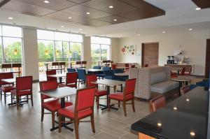 夏洛特夏洛特东北大学区智选假日酒店的餐厅设有桌椅和窗户。