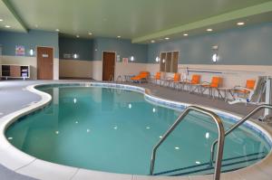 夏洛特夏洛特东北大学区智选假日酒店的医院里的一个大型游泳池,配有橙色椅子