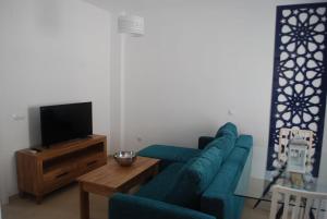 罗塔Apartamentos Costa de la Luz playa的客厅配有蓝色的沙发和电视