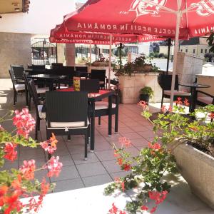 特尔古穆列什Continental Forum Tirgu Mures的一间带桌椅和红伞的餐厅