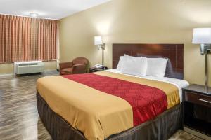 罗拉Econo Lodge near Missouri University of Science and Technology的酒店客房带一张大床和一把椅子