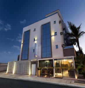 巴拉奈里奥-坎布里乌Concept Hotel Flat的一座白色的建筑,设有玻璃窗和棕榈树