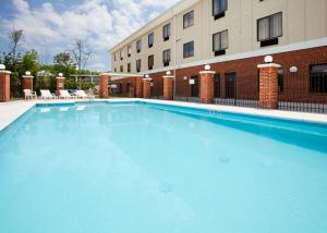 格林斯伯勒格林斯伯勒东快捷假日&套房酒店的大楼前的大型蓝色游泳池