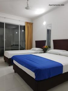 圣玛尔塔Apartamentos Playa Rodadero的两张位于酒店客房的床,配有蓝色和白色的床单