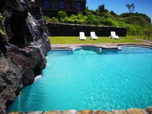 韦拉斯Hotel os Moinhos的一个带2把躺椅和岩石墙的游泳池