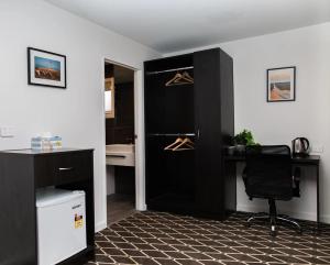 阿波罗湾ODYSSEY APOLLO BAY的客房设有带桌椅的黑色衣柜。