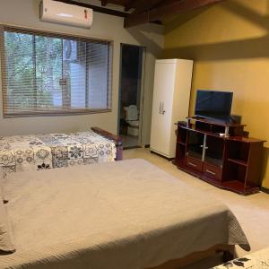 卡皮托利乌Chalés da Zelma的一间卧室配有两张床和一台平面电视