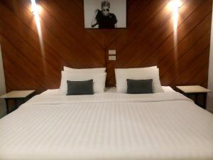清迈罗德曼酒店的卧室配有一张白色大床和木制床头板