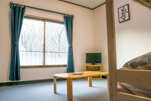 妙高Myoko House的一间卧室配有一张床、一张桌子和一个窗户。