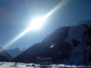 Gignod阿菲塔卡梅勒莎斯马格安酒店的太阳在雪覆盖的山上闪烁