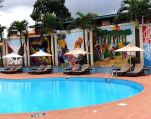 哈科特港哈科特港诺富特酒店的酒店前方的游泳池配有椅子和遮阳伞